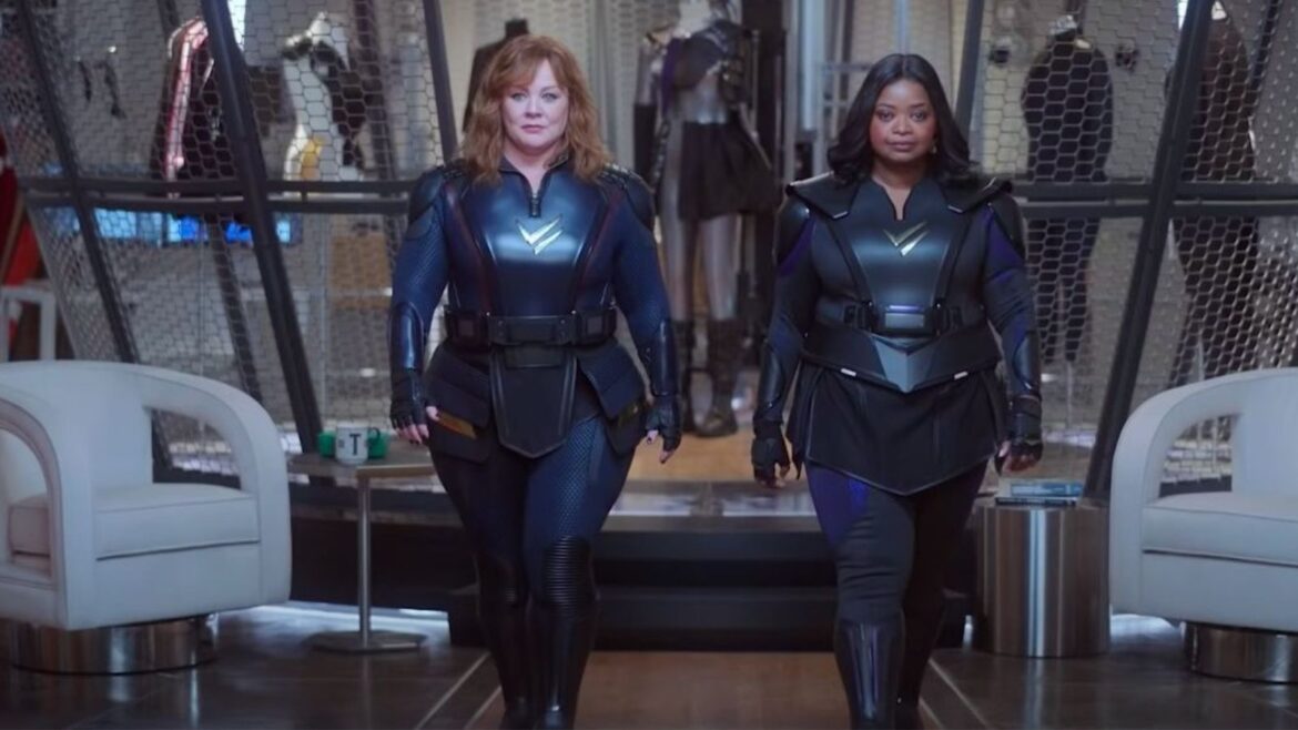 Two women in black and blue outfits walking down a hallway.