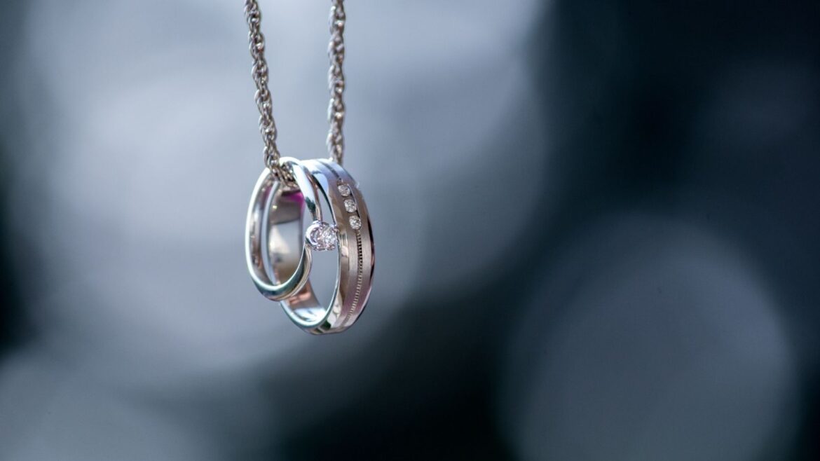 A silver necklace with two rings on it