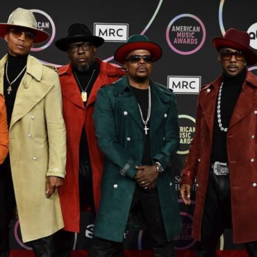 A group of men in coats and hats on the red carpet.