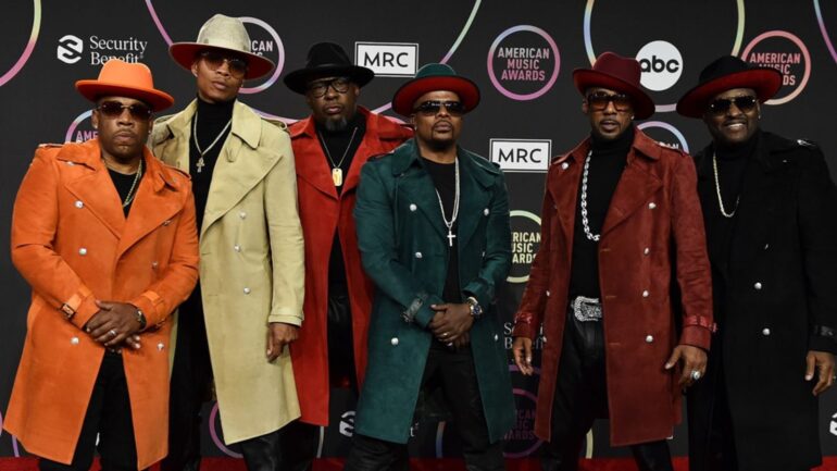 A group of men in coats and hats on the red carpet.