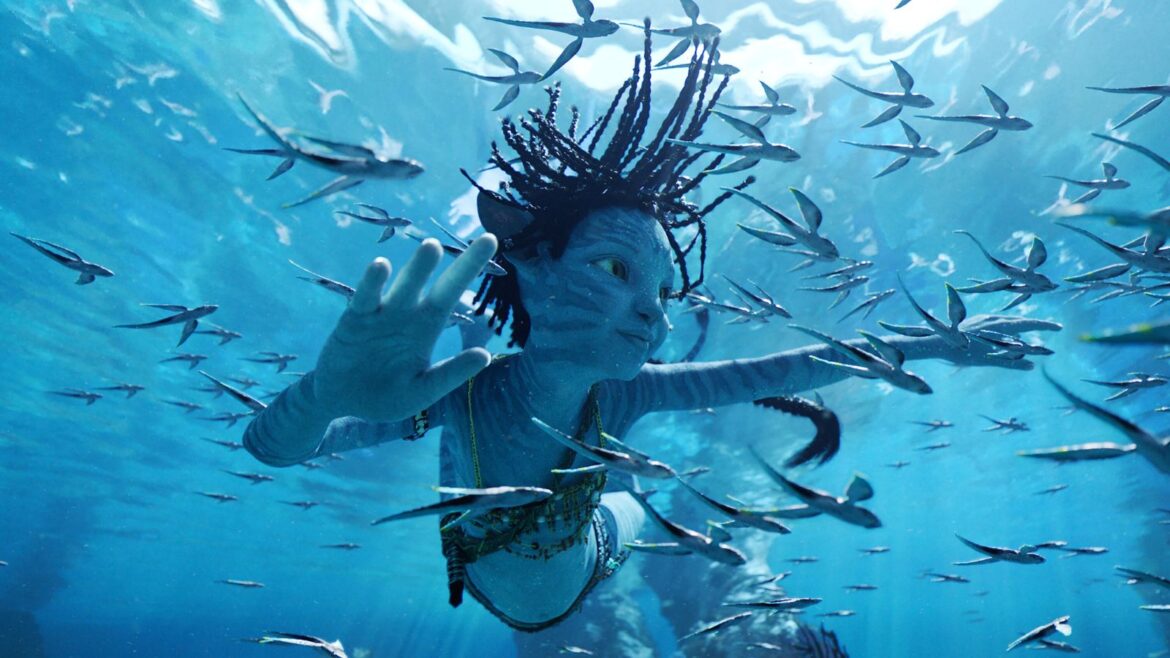 A woman swimming underwater with fish in the background.