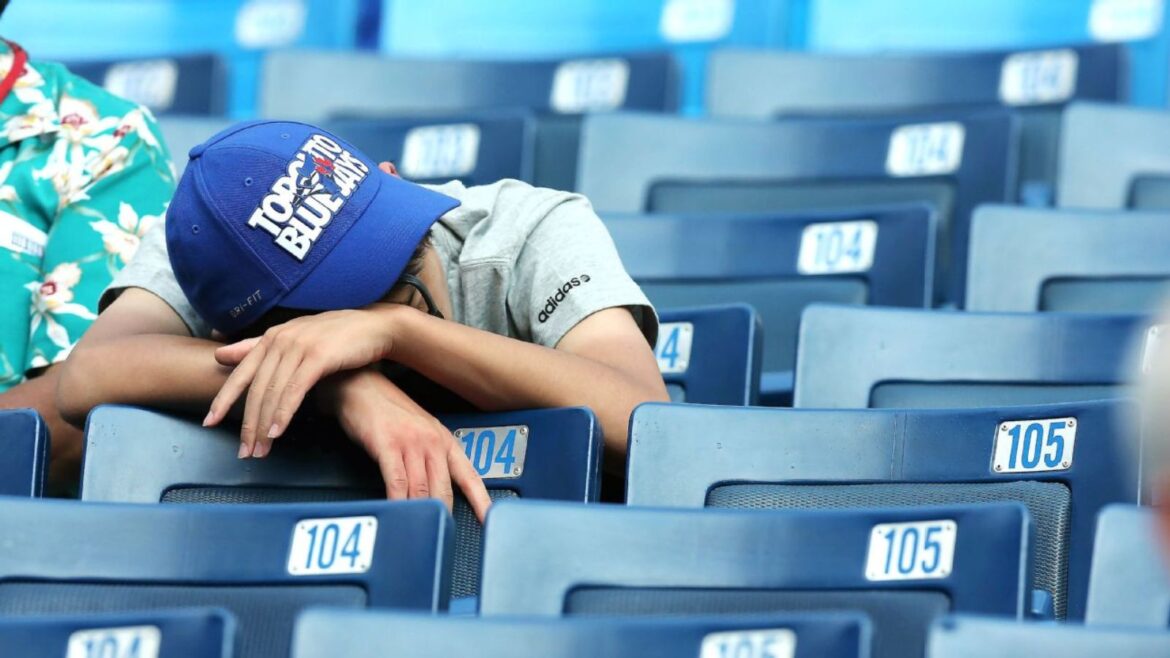 A man in blue baseball cap sleeping on top of seats.