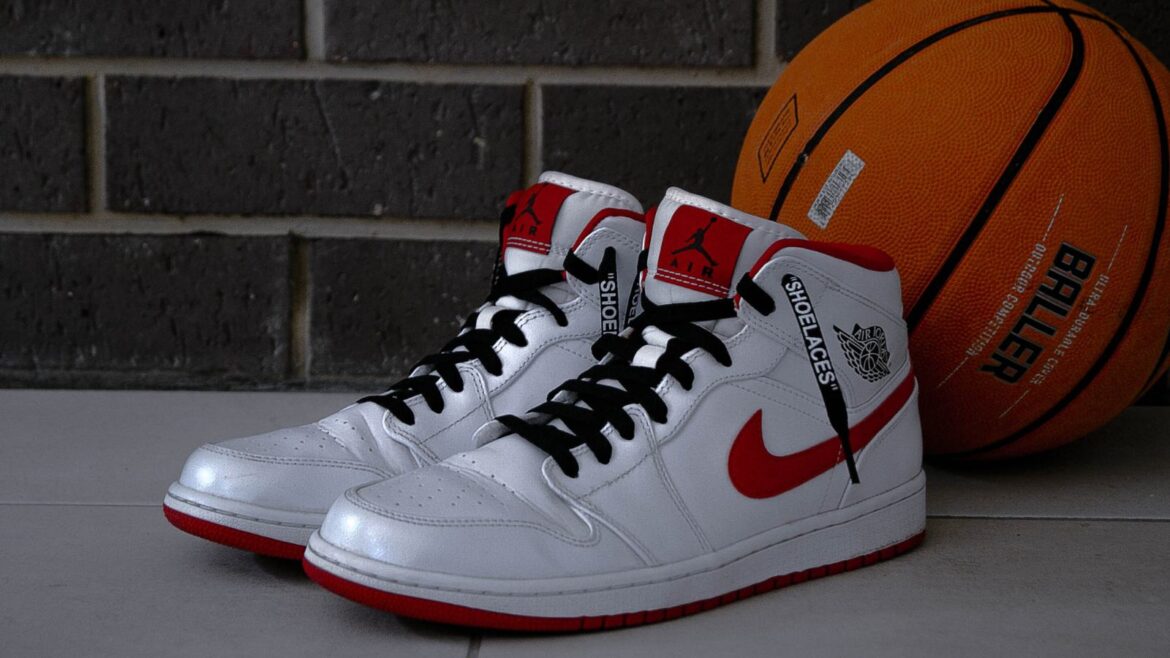 A pair of white and red sneakers sitting next to a basketball.