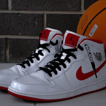 A pair of white and red sneakers sitting next to a basketball.