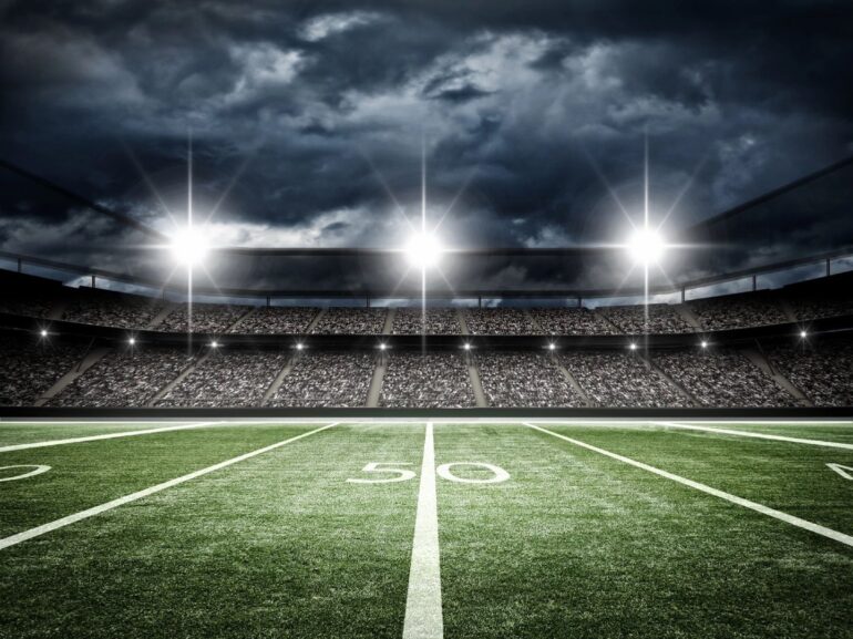 A football field with the lights on at night.